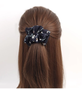 Detail of blue floral chiffon hair scrunchie with white flowers on a ponytail