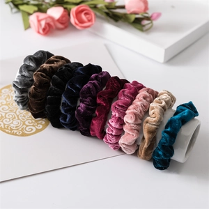 Dettaglio di elastici per capelli in velluto colorato su supporto bianco minimal