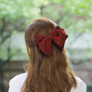 Detailed back view of a large burgundy chiffon triple-layered bow hair clip on a model