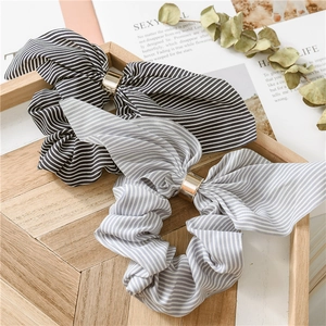 Striped chiffon scrunchies with bunny ears and gold metal buckles on a wooden tray