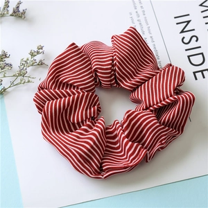 Detailed view of a red and white striped fabric scrunchie with soft ruffled texture
