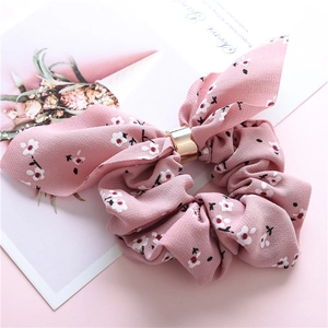 Detailed macro view of pink floral chiffon scrunchie with a gold metallic ring and bunny ears