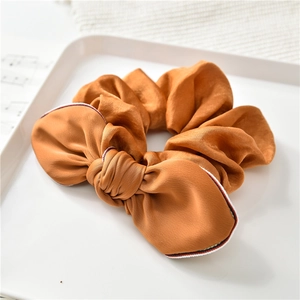 Dettaglio dell'elastico per capelli in seta bronzo con bordo a righe tricolore