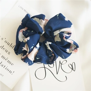 Close-up of dark blue floral chiffon scrunchie with delicate pink flower patterns