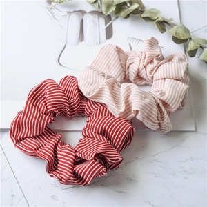 Minimalist striped fabric scrunchies in red and pink patterns on marble background