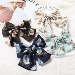 Floral chiffon bow hair clips in four elegant colors on a minimalist linen background