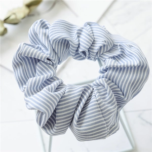 Detailed close-up of blue and white striped fabric scrunchie on marble surface