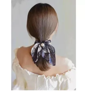 Detailed back view of a silk bow hair tie with a large pearl charm on a ponytail