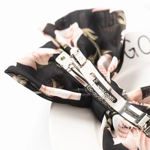 Close-up of metal spring clip mechanism on black floral chiffon bow hair accessory