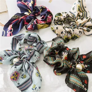 Detailed close-up of patterned satin scrunchies with long bow ribbons and pearl pendants