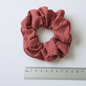 Detailed top view of red and white striped fabric scrunchie with measuring scale reference