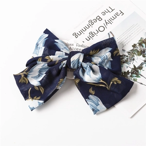 Detail of navy blue floral chiffon bow hair clip with elegant white flower pattern