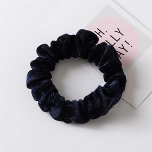 Dettaglio di un elastico per capelli in velluto blu scuro con trama morbida e pieghe