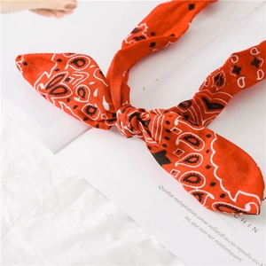 Detail of red paisley print headband with wired knot design on white textured background