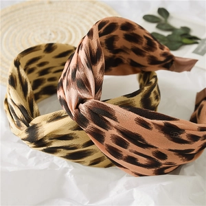 Detail of twisted leopard print headbands in yellow and red tones on rustic background