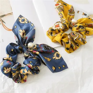 Detailed view of bohemian floral scrunchies featuring large pearls and long ribbons