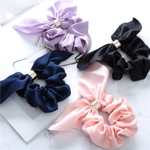 Elegant satin scrunchies set with rabbit ear bow and golden rings on marble background