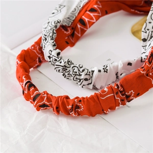Detail view of red and white paisley cotton headbands with elastic pleated texture