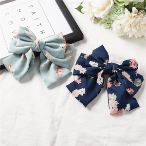 Detail view of large chiffon bow hair clips with floral patterns in blue and pink