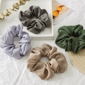 Close-up of four linen texture scrunchies in charcoal, purple, green, and brown tones