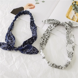 Flat lay of navy and white paisley bunny ear headbands on a decorative white background