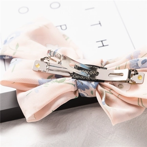 Macro detail of pink floral chiffon bow hair clip showing secure silver metal spring clasp