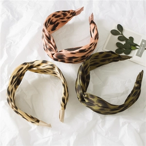Close-up of three leopard print twisted headbands in pink, yellow and olive satin fabric