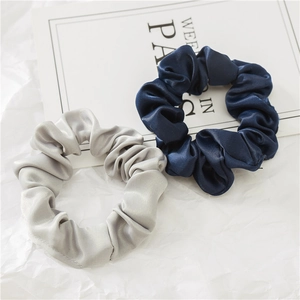 Gros plan de chouchous en satin de soie bleu marine et gris argenté au fini brillant