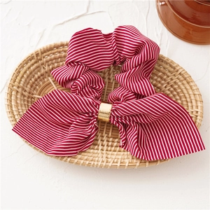 Detail of red and white striped chiffon scrunchie with a gold metal ring in a woven basket
