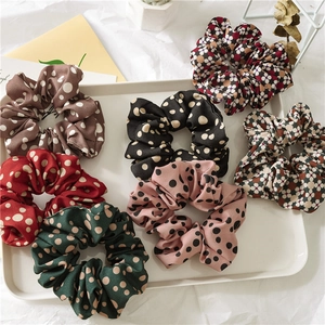 Set of 7 colorful polka dot scrunchies in chiffon fabric on a white display tray