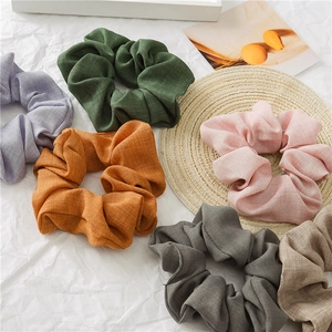 Detailed close-up showing six linen hair scrunchies in assorted earthy neutral tones