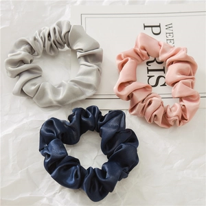 Vue détaillée de trois chouchous en satin en gris argent, rose et bleu marine