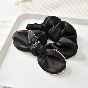Dettaglio di scrunchie in raso nero con eleganti bordi in nastro rosso bianco e blu