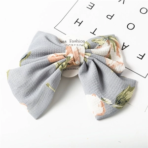 Detail of grey chiffon bow hair clip with floral bird print on a white background