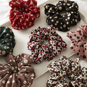 Detailed view of assorted polka dot and floral print scrunchies in a white display tray
