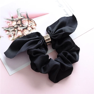 Close-up of black satin scrunchie with large bow and elegant gold metal ring detail