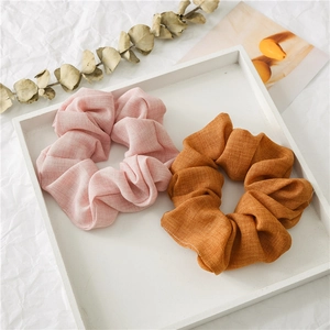 Detail of light pink and caramel linen scrunchies set on a minimalist white tray
