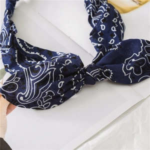 Close-up of dark blue paisley print headband featuring a twisted bow design and fine stitching