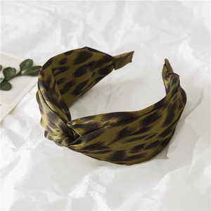 Close-up of olive green leopard print headband with knot design and satin texture