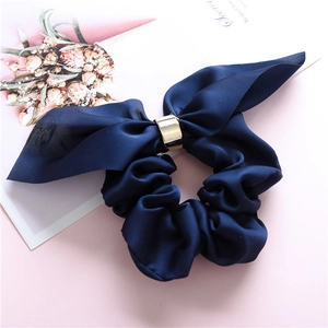 Detail of navy blue silk scrunchie with long ribbons and a gold metallic ring accent