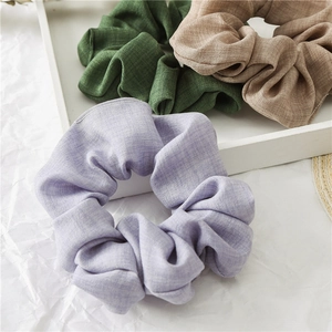 Detailed close-up of woven fabric scrunchies in purple, green and beige colors