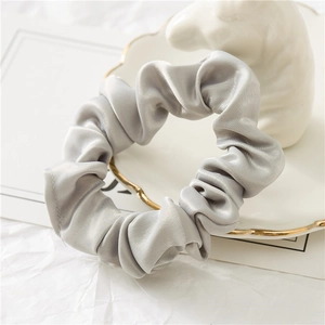 Gros plan d'un chouchou en satin gris argenté avec texture soyeuse et bande élastique