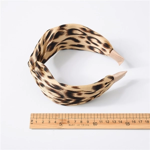 Detailed view of leopard print satin headband showing wide fabric twist and smooth texture