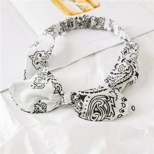 Close-up of bohemian white paisley bow headband with elastic strap on magazine background