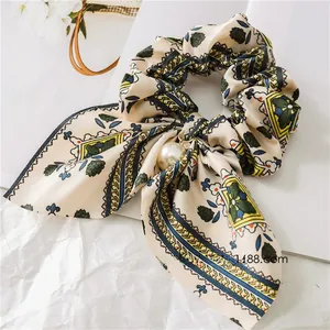 Detailed close-up of floral satin scrunchie with large pearl pendant and bow design