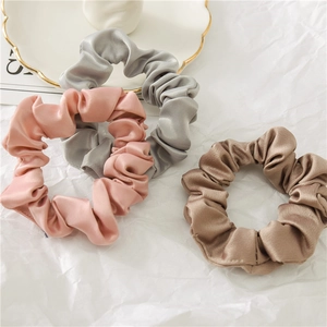 Gros plan de chouchous en satin rose, argent et champagne avec texture soyeuse