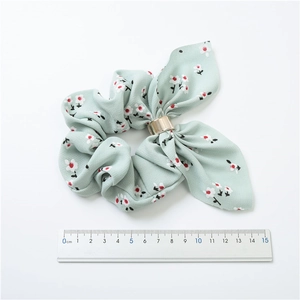 Detail view of a floral green scrunchie with bow showing 11cm measurement and gold ring