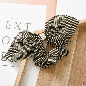 Detail of black and white striped chiffon scrunchie with a gold metal ring and bow design