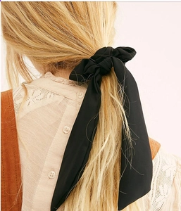 Detail view of a black chiffon bow hair tie with long ribbons on a blonde low ponytail