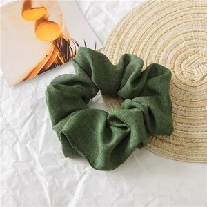 Detail of dark green cotton linen scrunchie showing rich woven texture and fabric folds